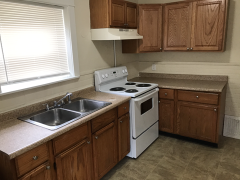 A kitchen with a white stove and wooden cabinets.
