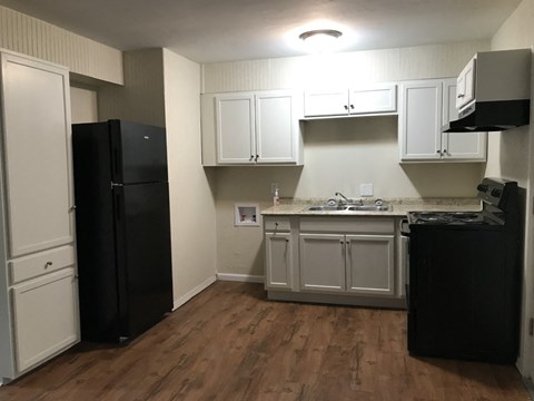 A kitchen with black appliances and white cabinets.
