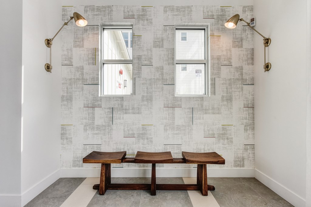 Seating Area with Wooden Bench, Windows, and Wall Mounted Lamps at Morgan Ranch Apartments, California