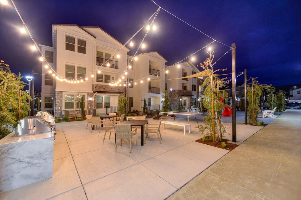 BBQ and Outdoor Seating Area at nighttime with white lights strung back and forth across the area at Morgan Ranch Apartments, Morgan Hill, California