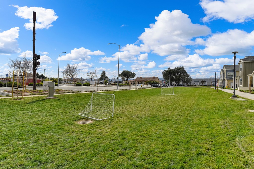 Grassy area with two smaller soccer goals set up.  Sky is bright blue with large white clouds at Morgan Ranch Apartments, Morgan Hill, CA, 95037