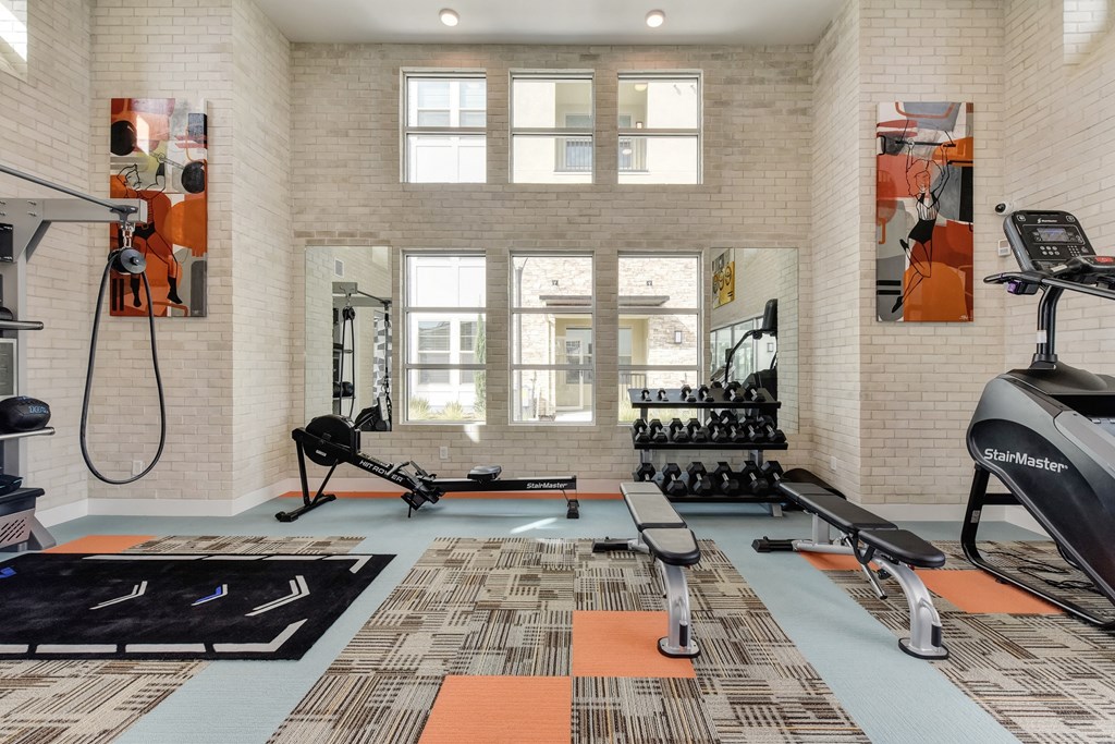 Fitness center with benches, free weights and rowing machine at Morgan Ranch Apartments, Morgan Hill, CA