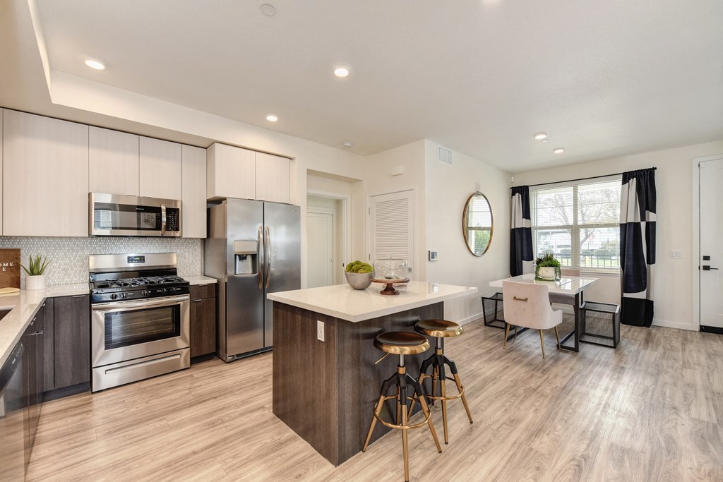 kitchen with white cabinets, stainless steel appliances and island counter space with seating at Morgan Ranch Apartments, California, 95037