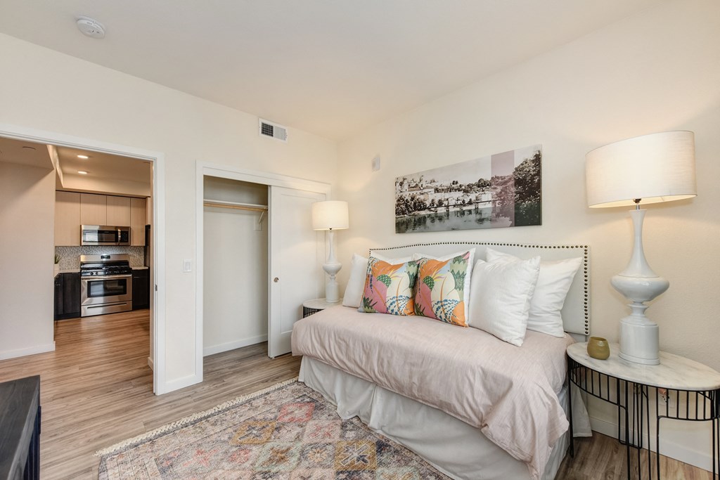 Bedroom with daybed, closet doors open to show available space, area rug and wall art above the bed at Morgan Ranch Apartments, Morgan Hill, 95037