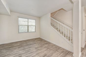 Townhome with staircase leading to the upstairs area.  Room has hardwood inspired flooring and large window.