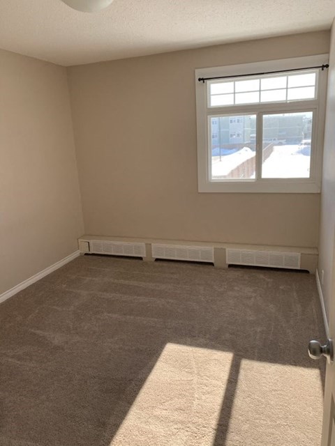 A room with a window and a carpeted floor.