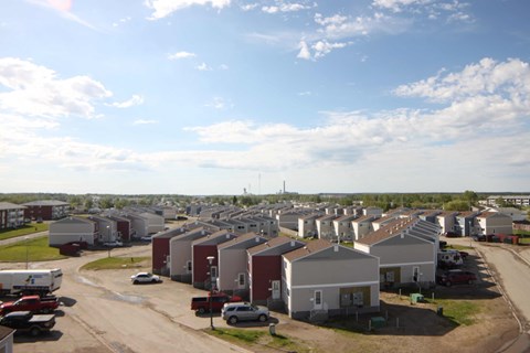 A sunny day in a residential area with houses and cars.