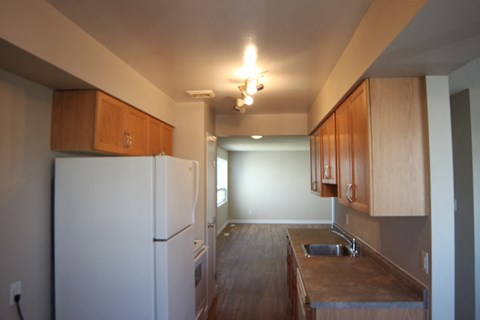 A kitchen with a white fridge and wooden cabinets.