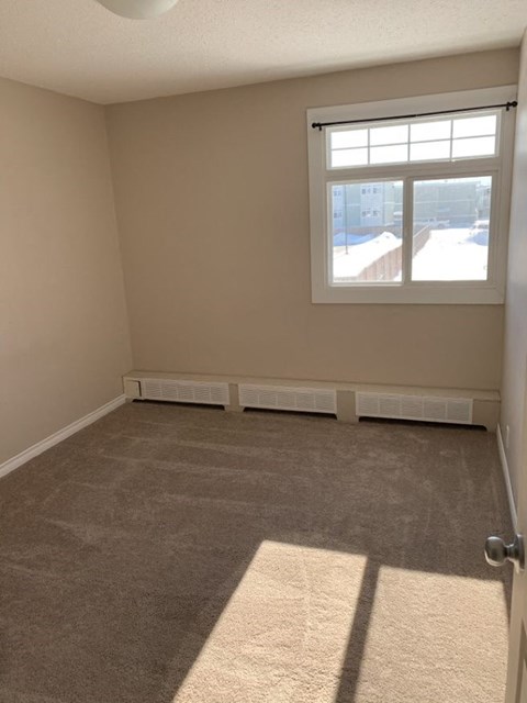 an empty living room with a window and carpet