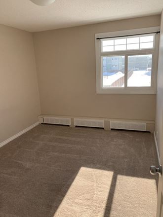 an empty living room with a window and carpet