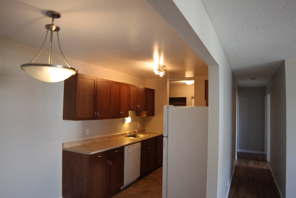 an empty kitchen with a white refrigerator and wooden cabinets