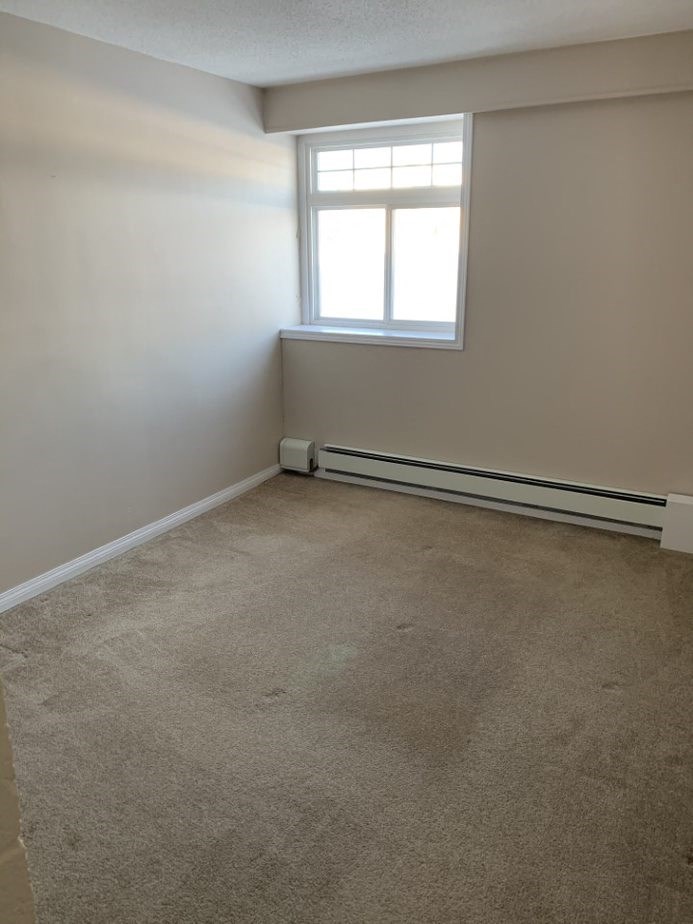 an empty room with a window and a carpet