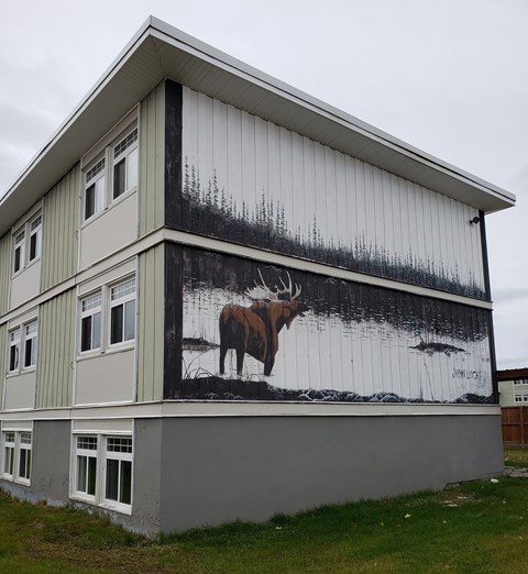 A building with a moose painting on the side.