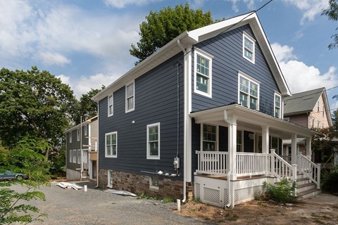 A blue house with white railings and a porch.
