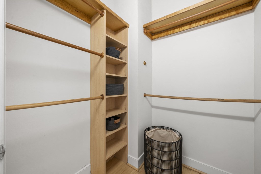 a walk in closet with shelves and a trash can