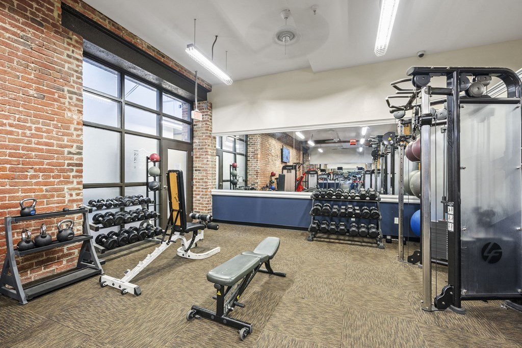 a gym with weights and cardio equipment and a large window