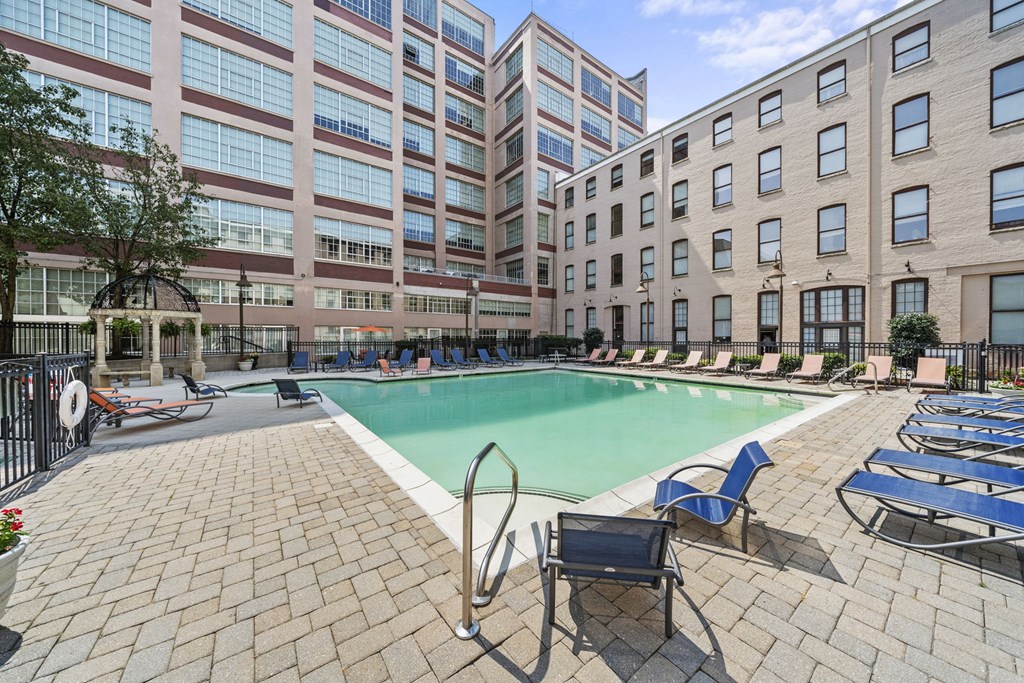a swimming pool with chairs and a building in the background