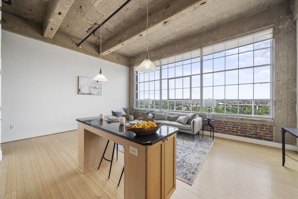 a living room with a large window and a table with a bowl of fruit