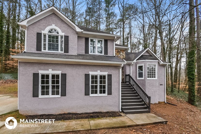 a small gray house with black stairs and trees