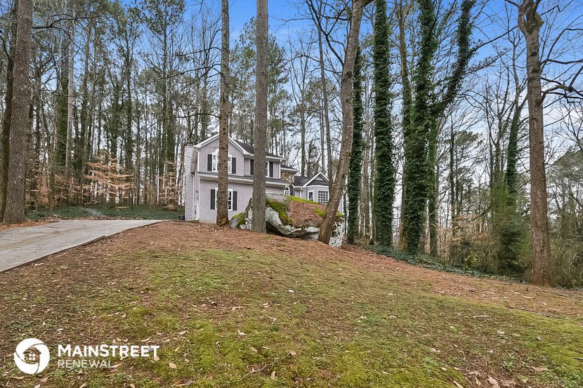 a white house sitting on top of a hill in the woods