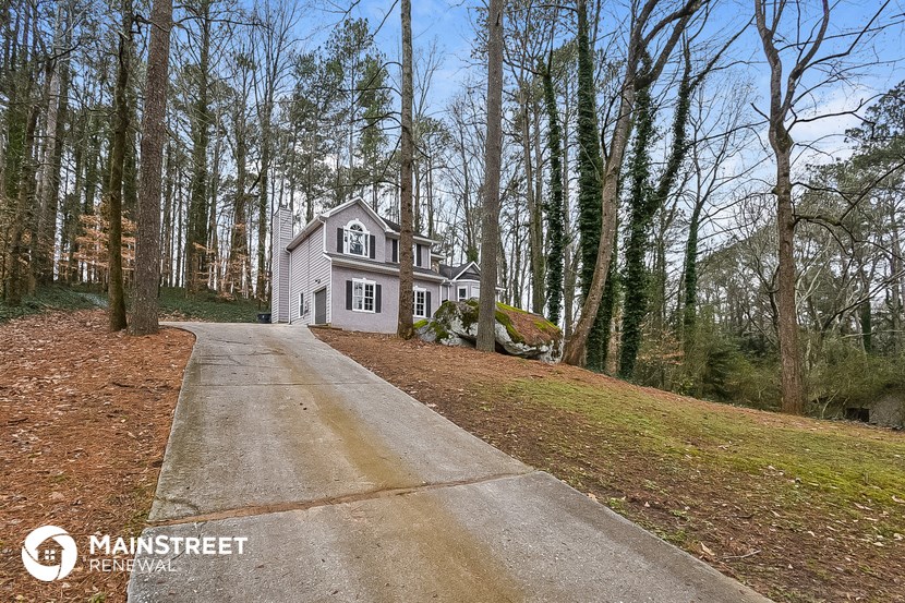 a white house on the side of a road in the woods