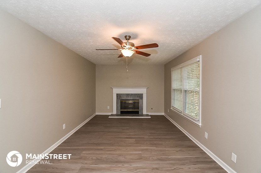 the spacious living room with fireplace and ceiling fan
