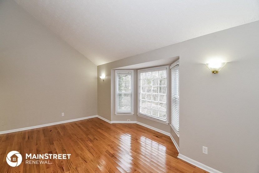 the spacious living room with hardwood flooring and large windows
