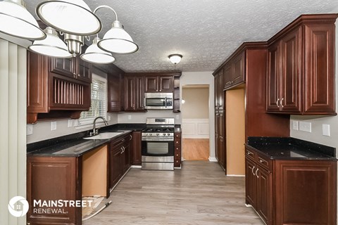 a kitchen with wood cabinets and black counter tops and a wood floor