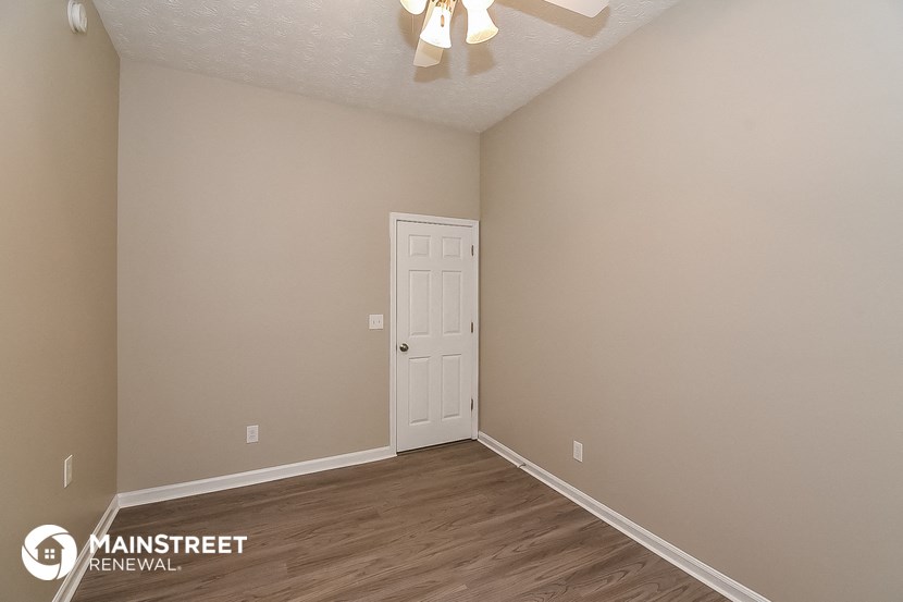 the spacious living room of an apartment with a white door