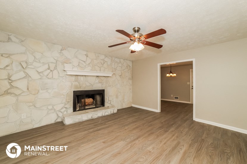 a living room with a fireplace and a ceiling fan