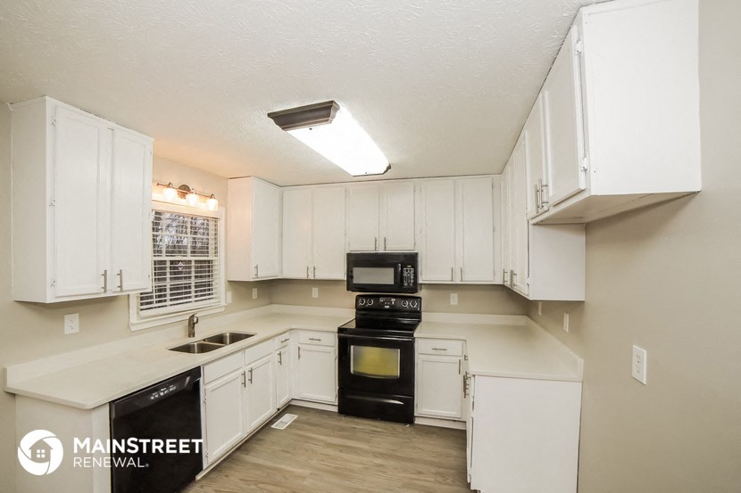 a white kitchen with black appliances and white cabinets