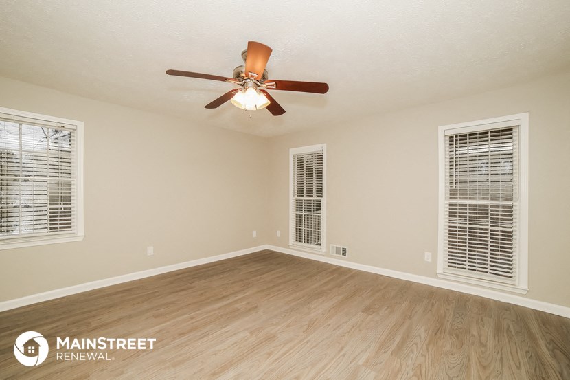 an empty living room with a ceiling fan and windows