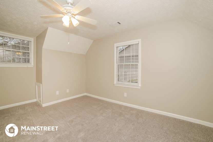 the upstairs bedroom has a carpeted floor and a ceiling fan