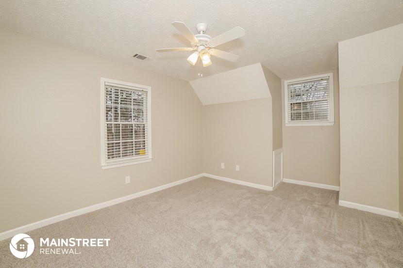 the living room of an empty home with a ceiling fan