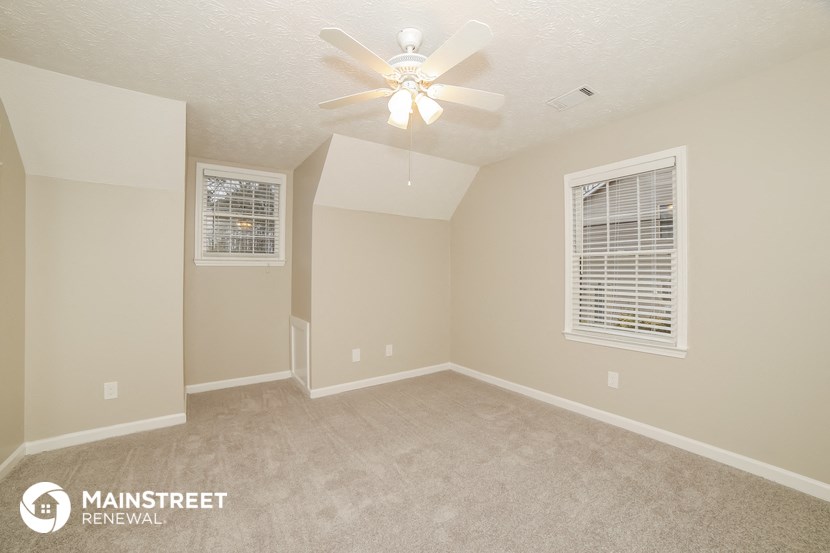 the spacious upstairs bedroom with ceiling fan and carpeting