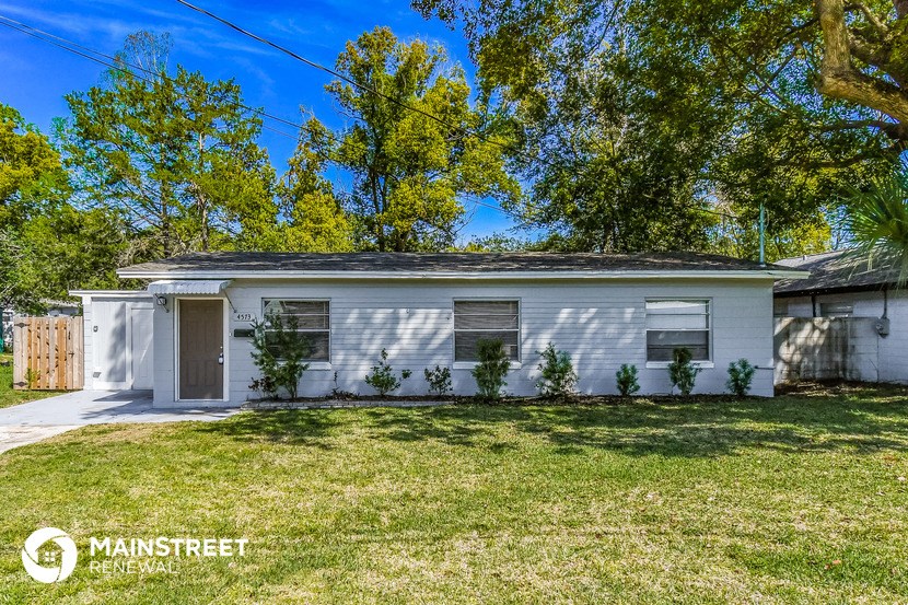 a small white house with a lawn and trees