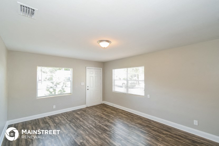 the spacious living room with wood flooring and white walls