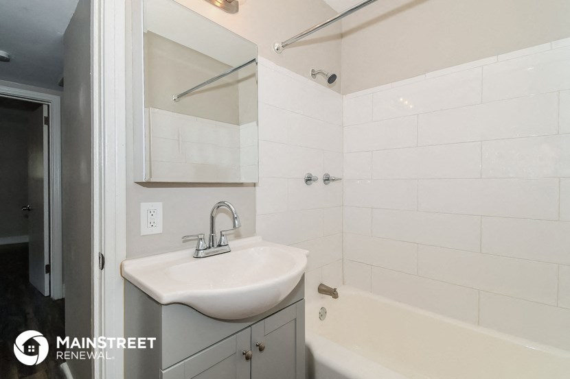 a small bathroom with a sink and a tub and a mirror