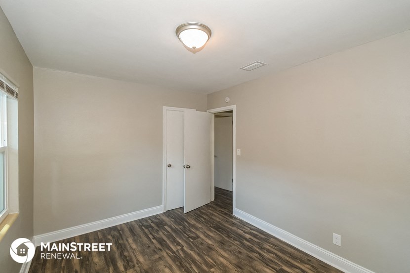 the spacious living room with wood flooring and white walls