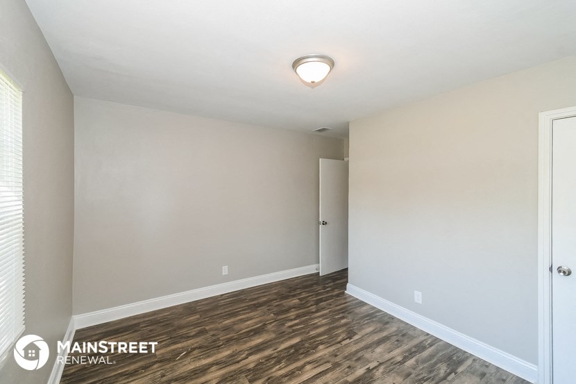 the spacious living room with wood flooring and white walls