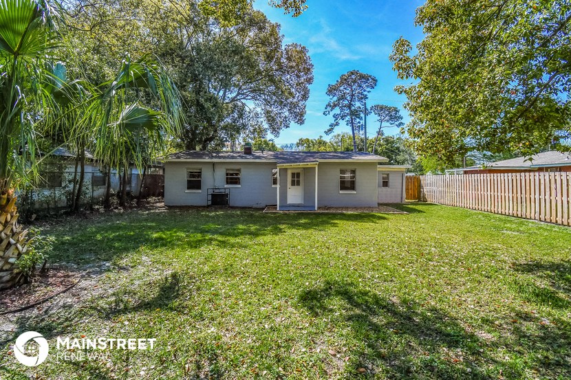 a small white house with a yard and a fence