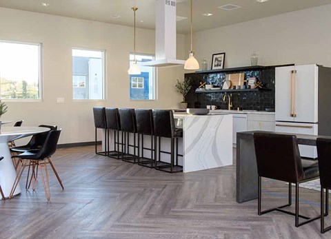A modern kitchen with black chairs and a white counter.