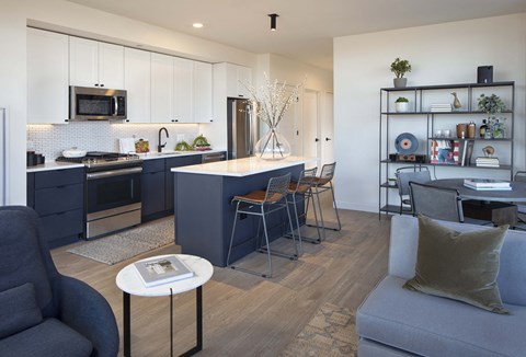 a kitchen and living room with a blue island and white cabinets