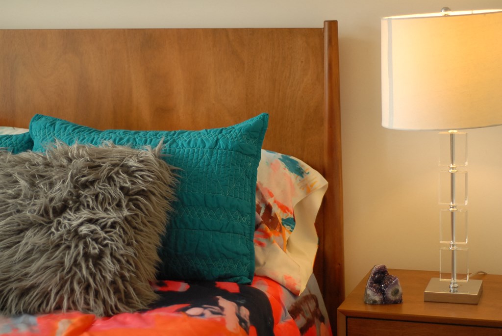 a bed with pillows and a nightstand with a lamp