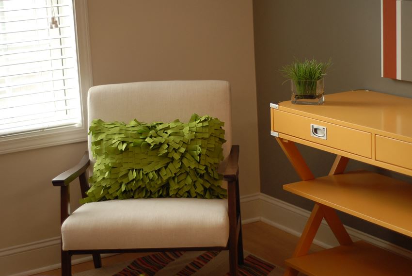a chair with a green pillow in a room with a desk