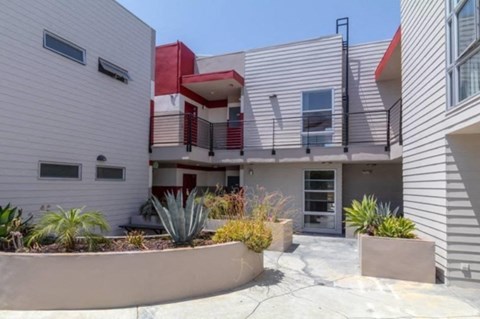 A modern house with a red accent wall and a landscaped front yard.