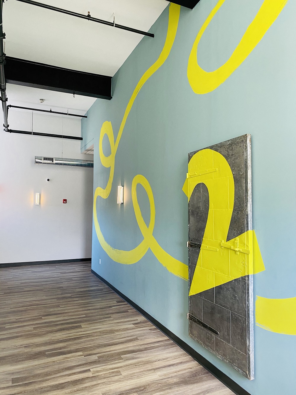 a room with a blue wall with a yellow abstraction on it