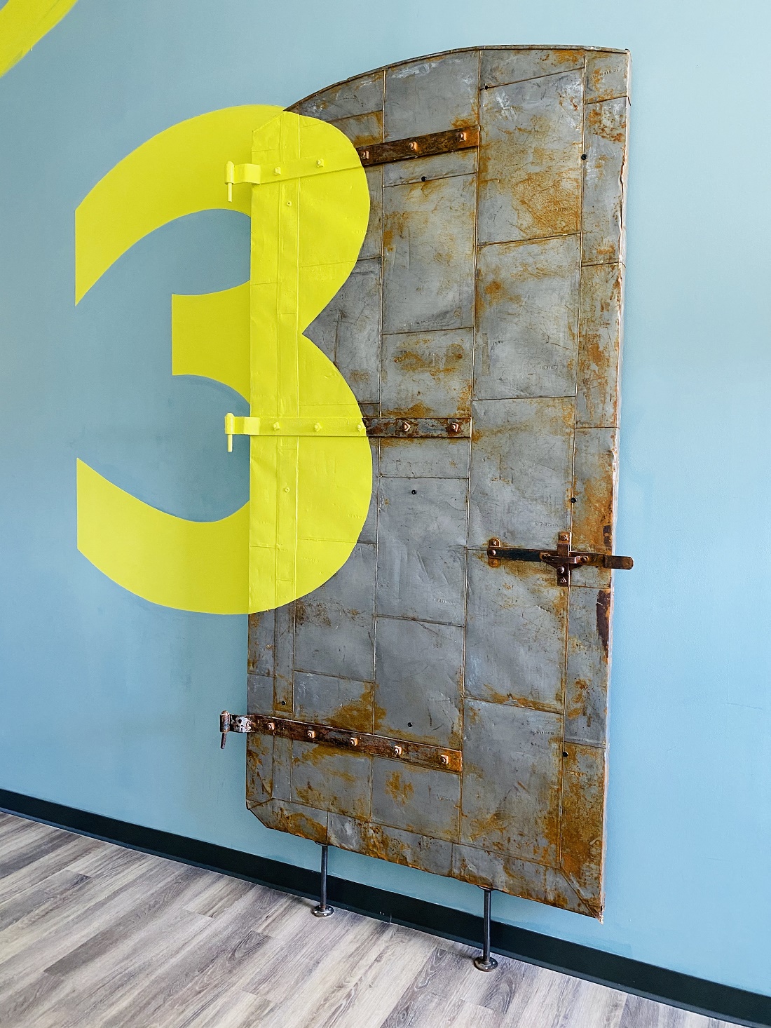 a door with a large yellow number three on a blue wall