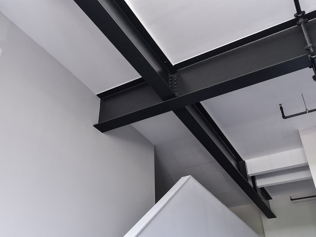 a view of the ceiling of a building with black beams and white walls