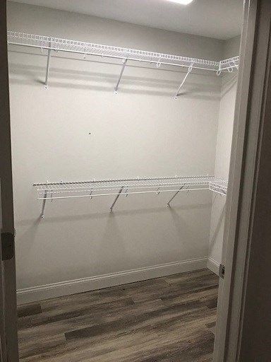 an empty closet with white shelves and a wood floor